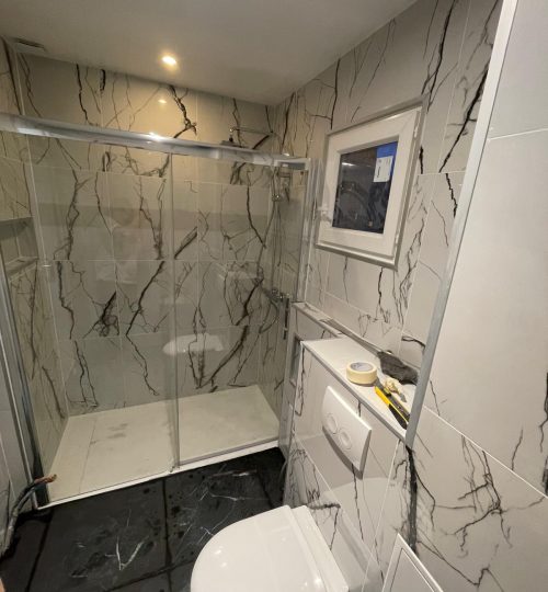 Rendu final – salle de bain moderne et fonctionnelle Faïence marbrée, douche vitrée, WC suspendu, éclairage LED.